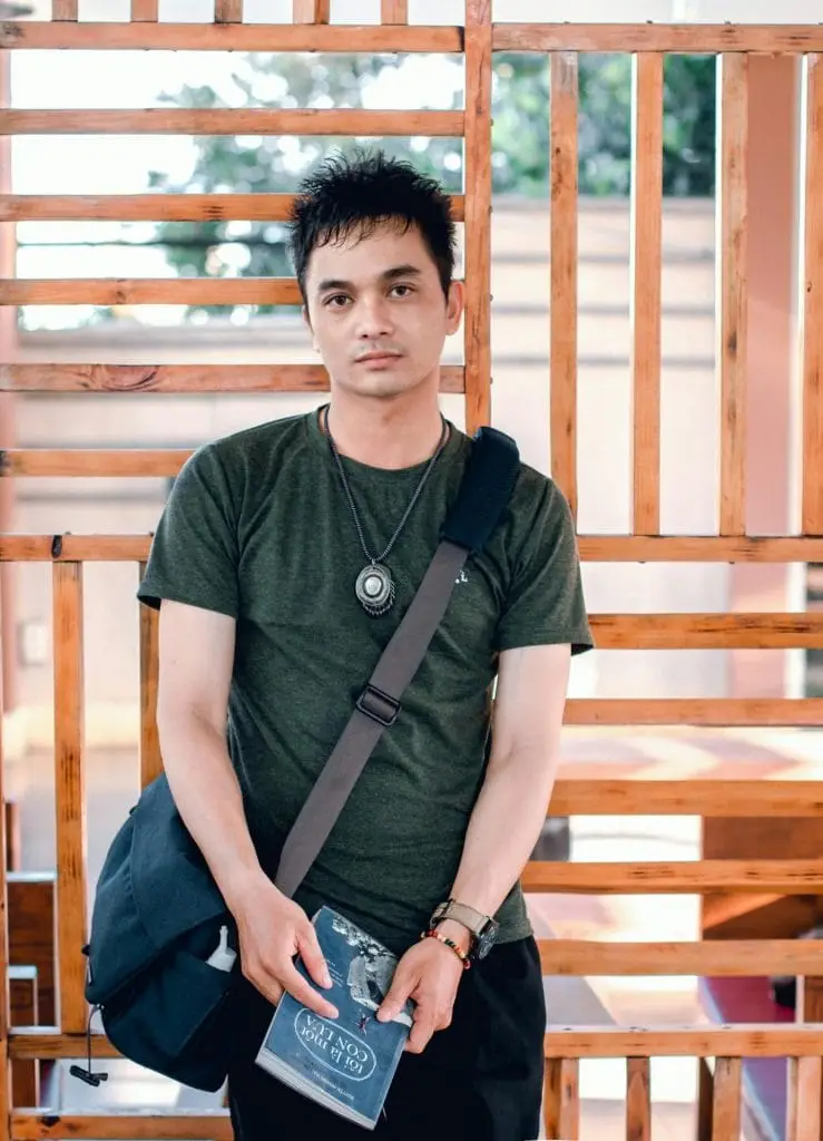 a man standing in front of a wood fence