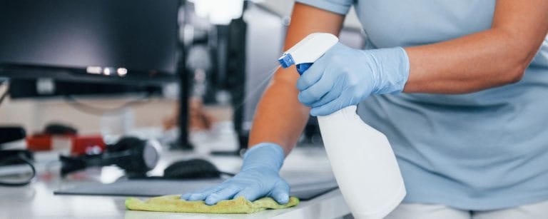 Close up view of woman in protective gloves that cleaning tables in the office